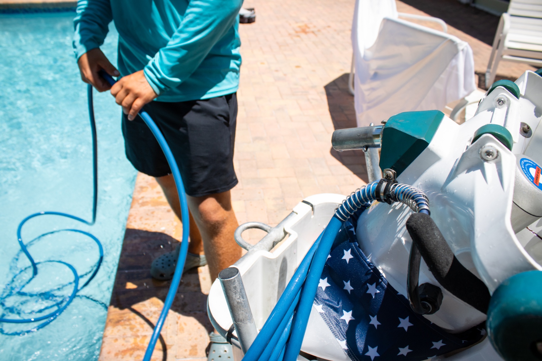 Pool technician deploying a Riptide pool vacuum hose for cleaning at a Palm Beach County home